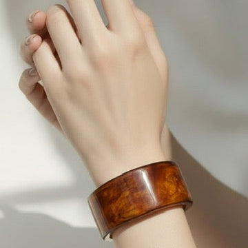 Hand wearing a wooden bracelet on a light background