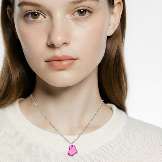 Woman wearing a necklace with a pink heart pendant on a plain background