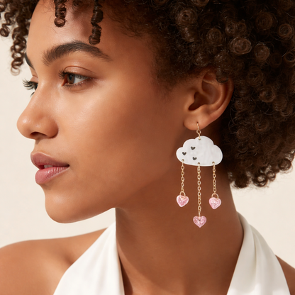 Woman wearing cloud-shaped earrings with heart charms on a neutral background