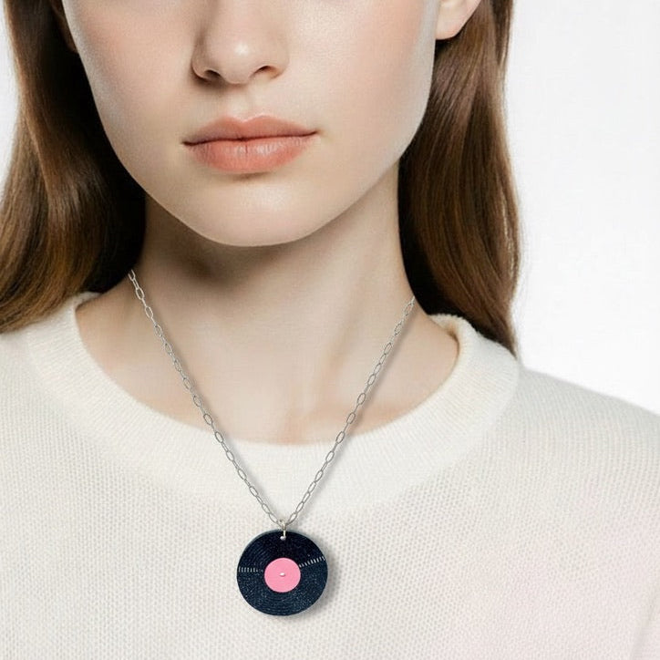 Woman wearing a necklace with a circular pendant on a plain background